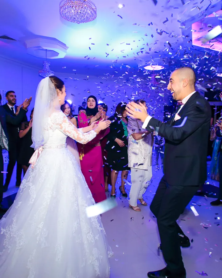 Mariés qui dansent sous les confettis pendant la soirée